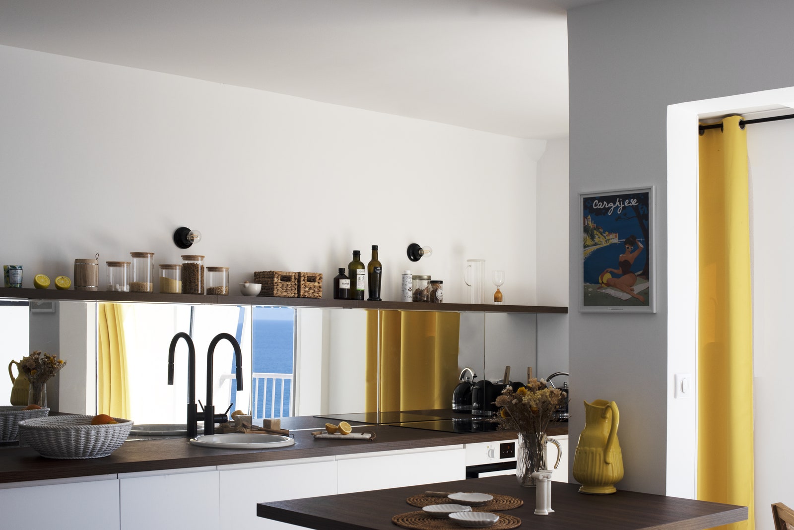 White base units covered in a mirrored credenza occupies the entire kitchen wall.  Worktop and shelf...