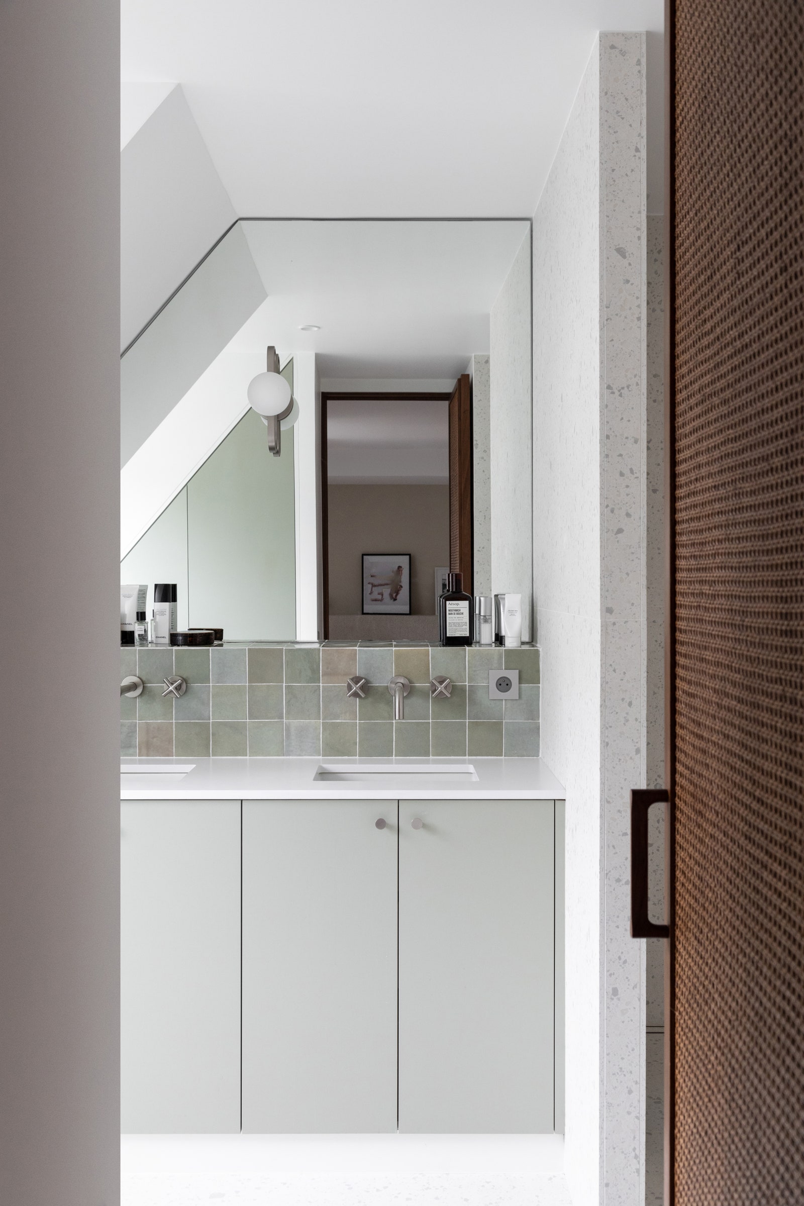 The reed door contrasts with the large terrazzo-style tiles and imitation ceramic tiles...