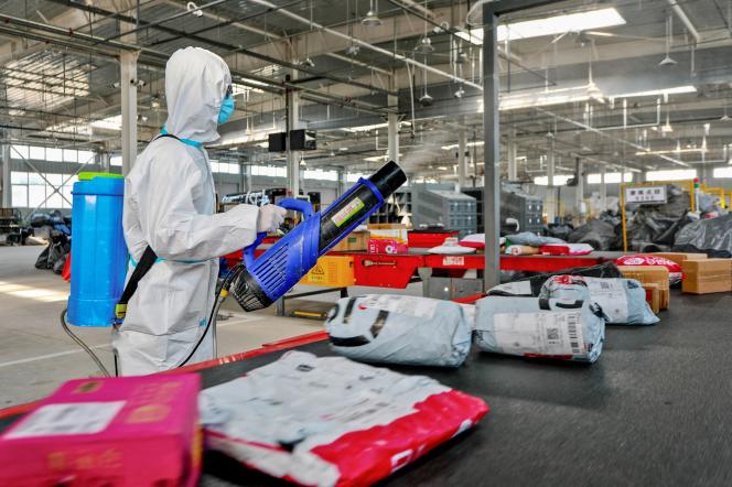 Un employé d'une entreprise de logistique pulvérise du désinfectant sur des colis à livrer, à titre préventif, à Zhangye, en Chine, le 16 November 2021.