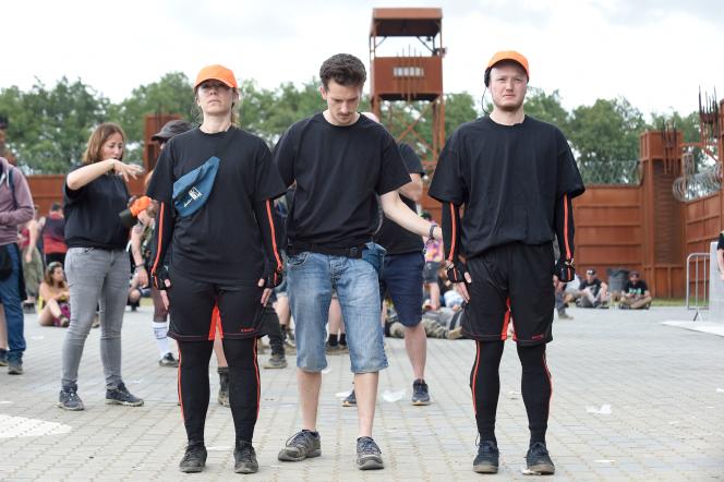 Two scientists involved in studying crowd movements during Hellfest are equipped with sensors and wear orange hats to be visible.  In Cleeson, June 26, 2022.