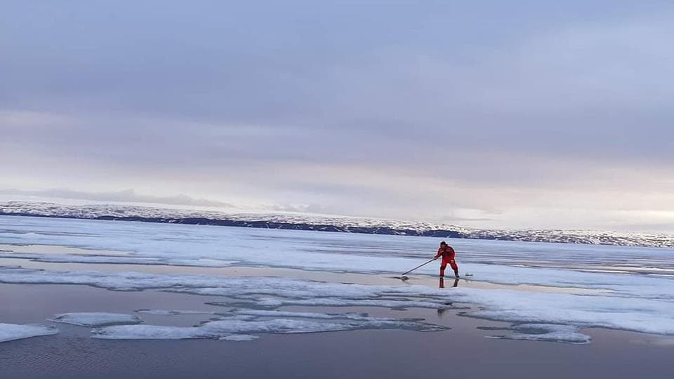 A fisherman catches a seal on the ice, in June 2022.