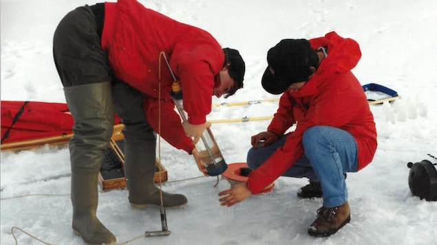 Two students take water samples from the ice near Iqaluit in April 1998.